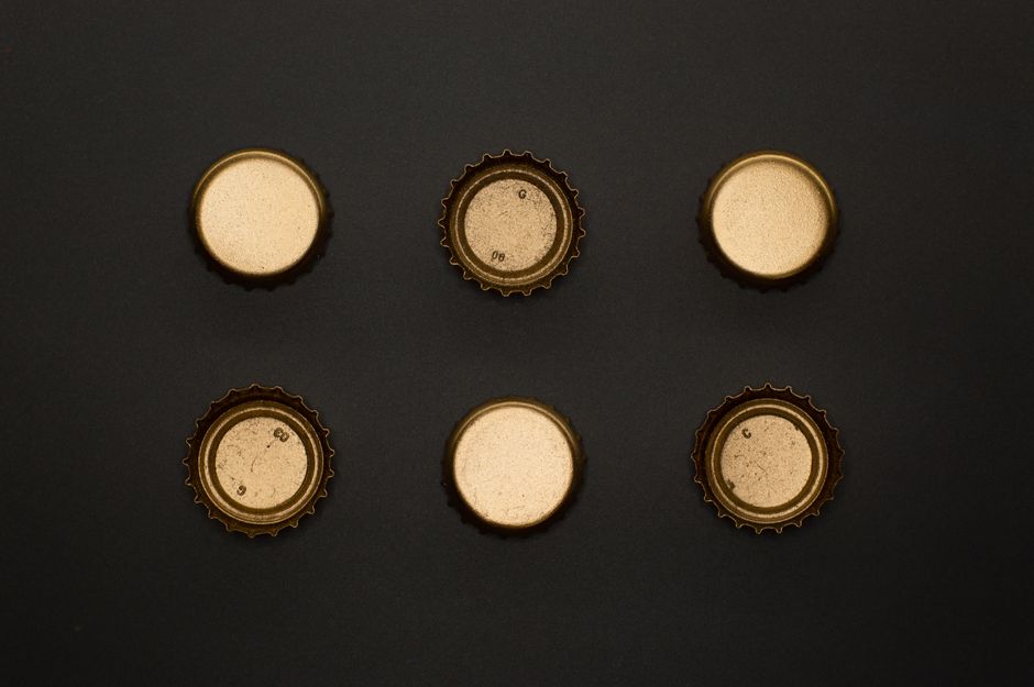 Artistic arrangement of bottle caps on a black background, capturing a minimalist aesthetic.