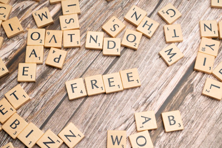 Scattered wooden letter tiles spelling 'FREE' placed on a rustic wooden floor.