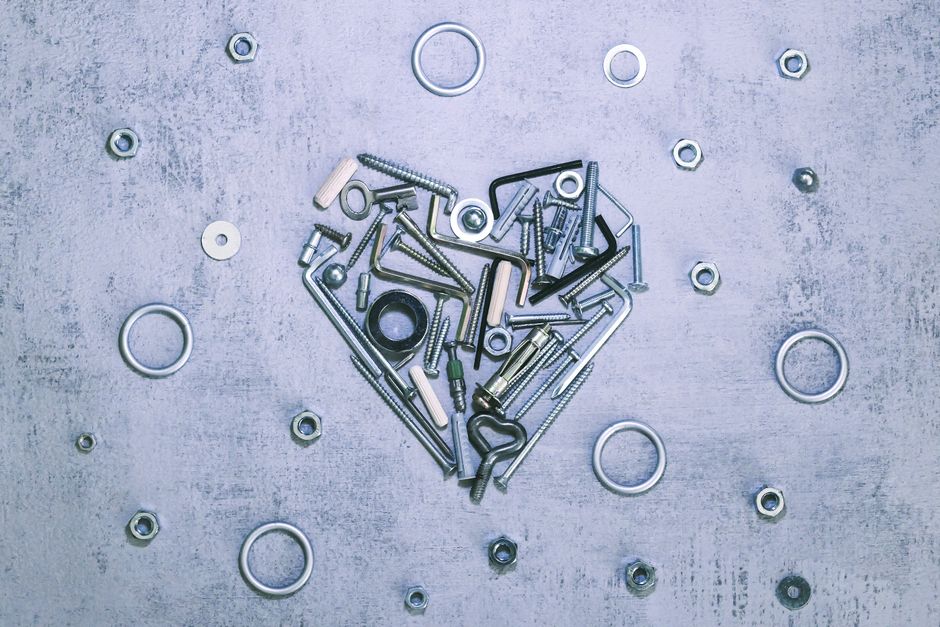 A creative heart shape composed of screws, bolts, and nuts on a textured surface, symbolizing love for craftsmanship.