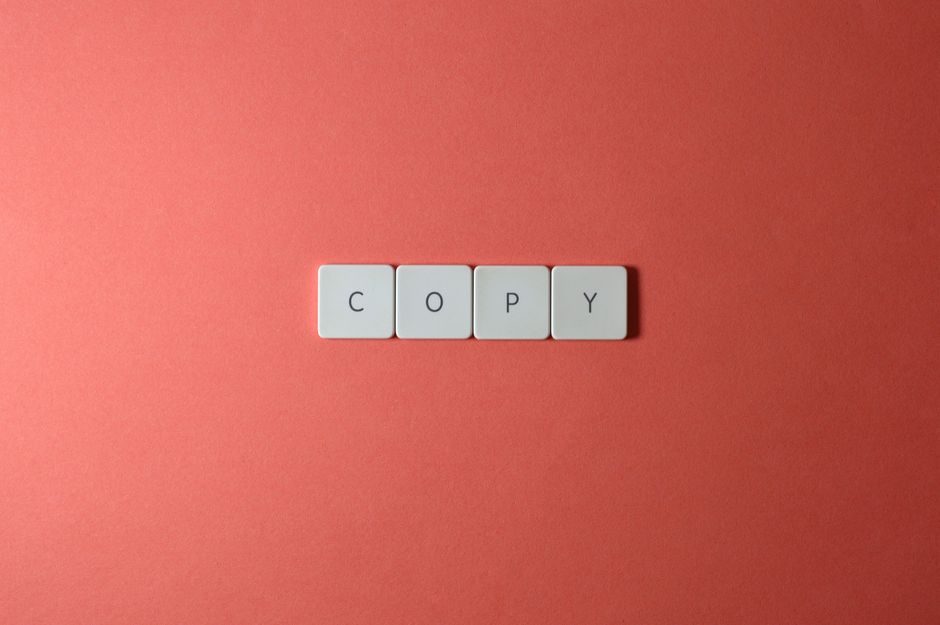 Simple arrangement of keyboard keys spelling 'COPY' on a coral surface, perfect for creative concepts.
