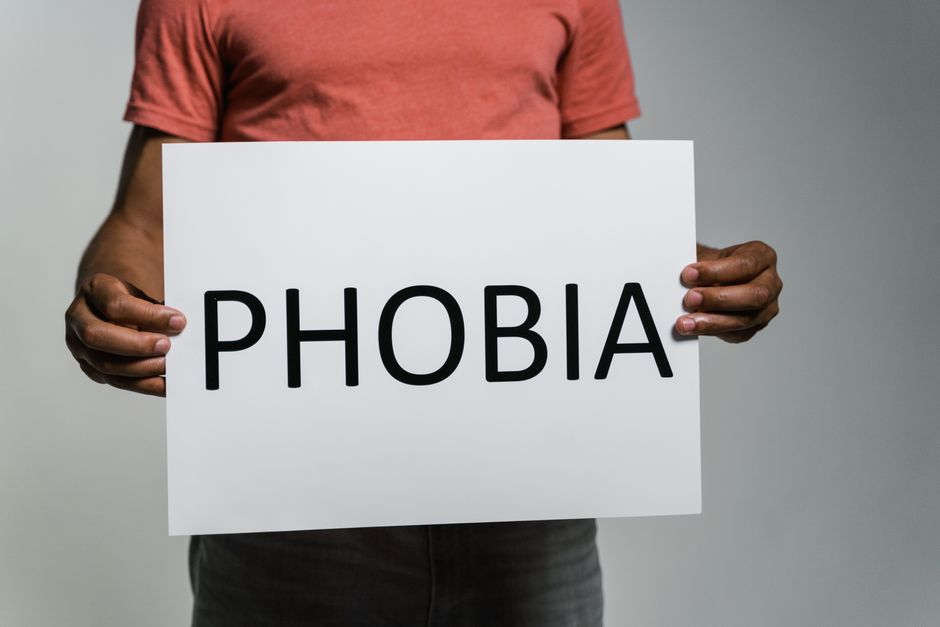 Adult holding a sign with 'Phobia' to convey fear and anxiety concepts.