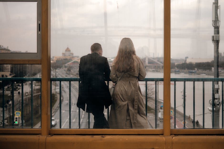 Two people enjoy the view of Moscow from a bridge, featuring urban and river scenery.