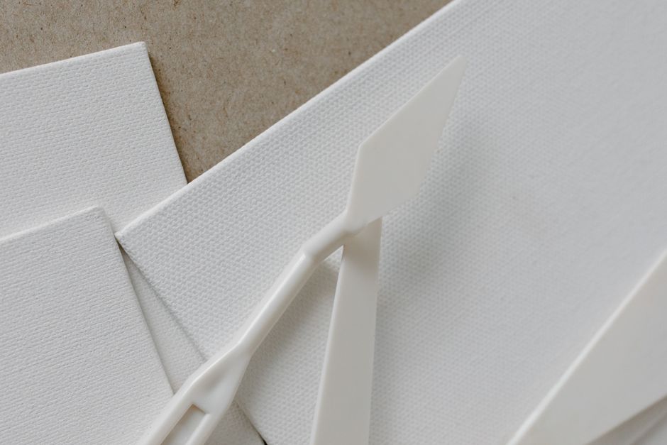 Minimalist close-up of white canvas with palette knives, ideal for art concepts.