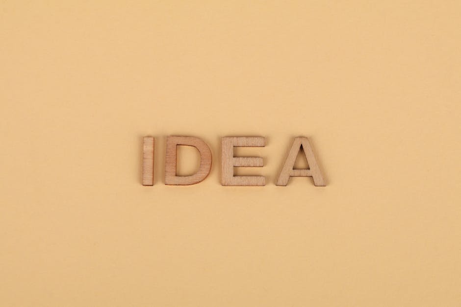 Wooden letters forming 'IDEA' on a plain beige surface, representing creativity.