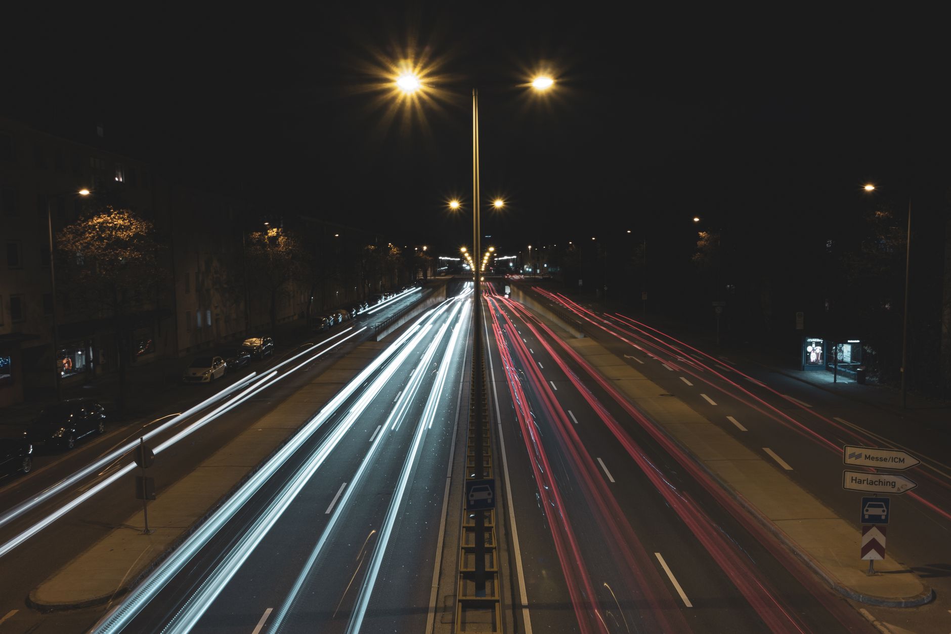 Long exposure cars driving on multiple lane road in suburb at night