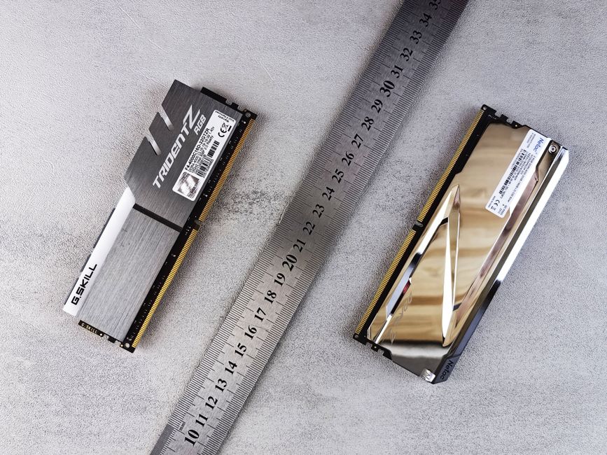 Close-up of computer memory modules and metal ruler placed on a textured gray surface.
