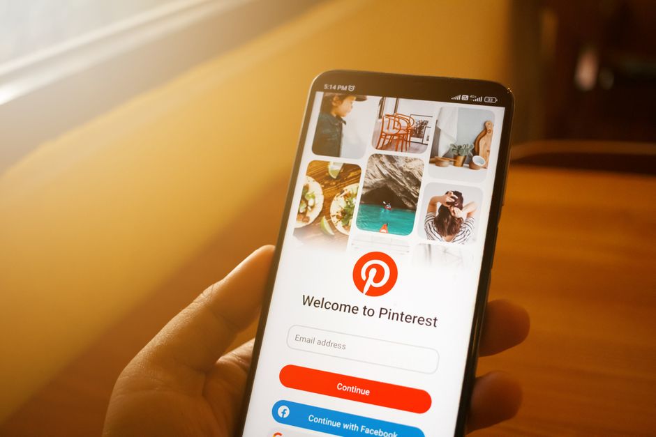 Close-up of smartphone displaying Pinterest login screen in a cozy indoor setting.
