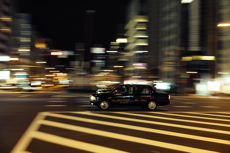 Dynamic city night scene featuring a taxi in motion blur crossing an urban intersection.