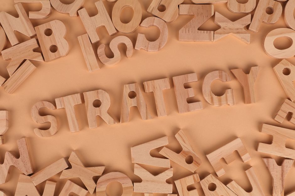 Overhead view of wooden letter blocks spelling 'Strategy' on a soft brown background.