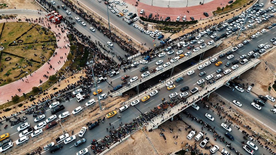 A dynamic aerial shot capturing heavy traffic flow on a multilayered highway in Iraq, showing urban life.