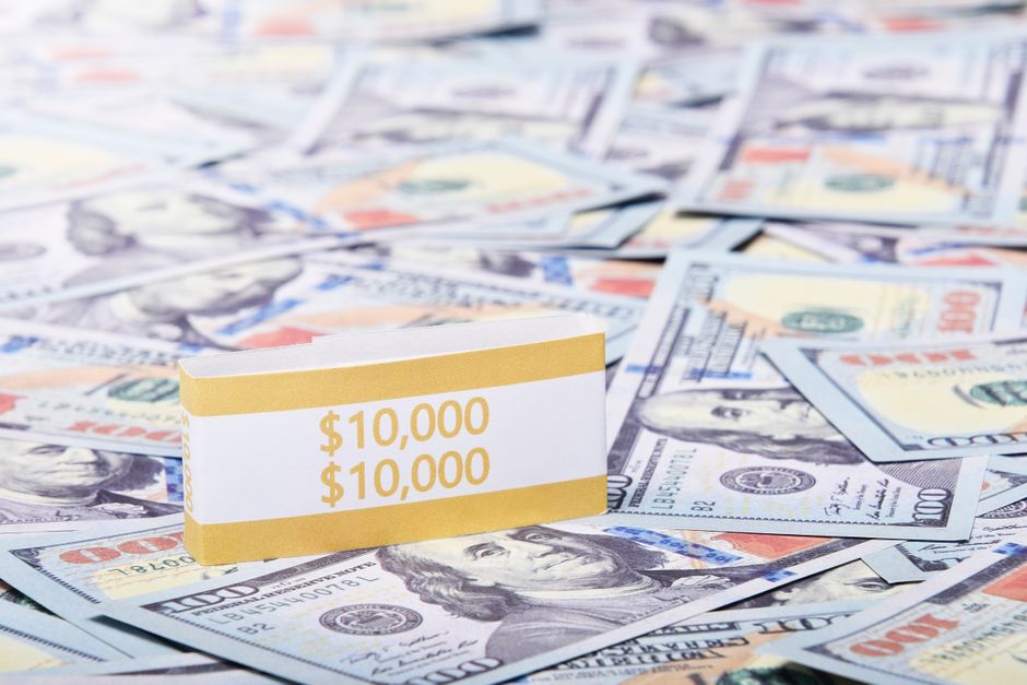 Close-up of a $10,000 stack of US dollars with a currency band, highlighting wealth and finance.