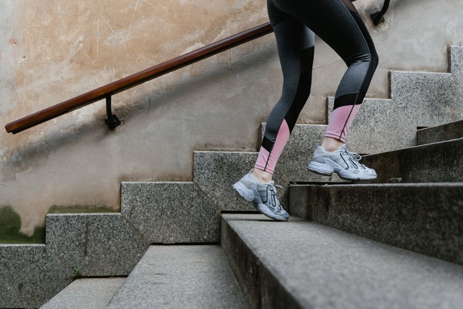 A woman in stylish leggings and sneakers climbing stairs outdoors, symbolizing fitness motivation.