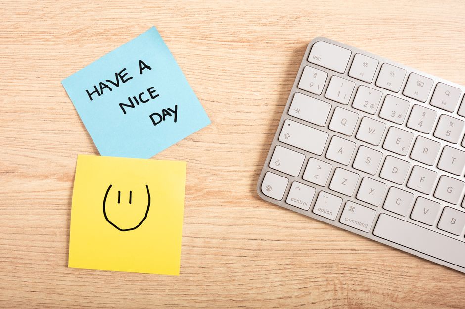 A cheerful desk setup with a note saying 'Have a Nice Day' next to a keyboard.