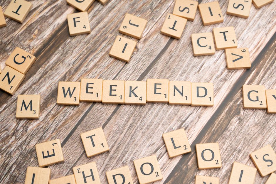 Wooden Scrabble tiles spelling 'weekend' on a rustic wooden table.