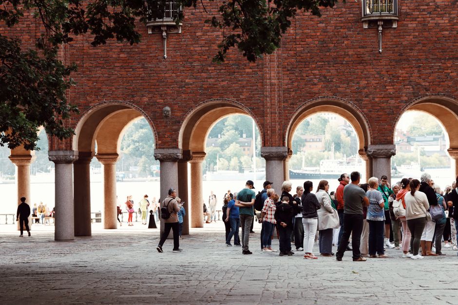 A group of tourists congregate under historic arches in Stockholm, Sweden.