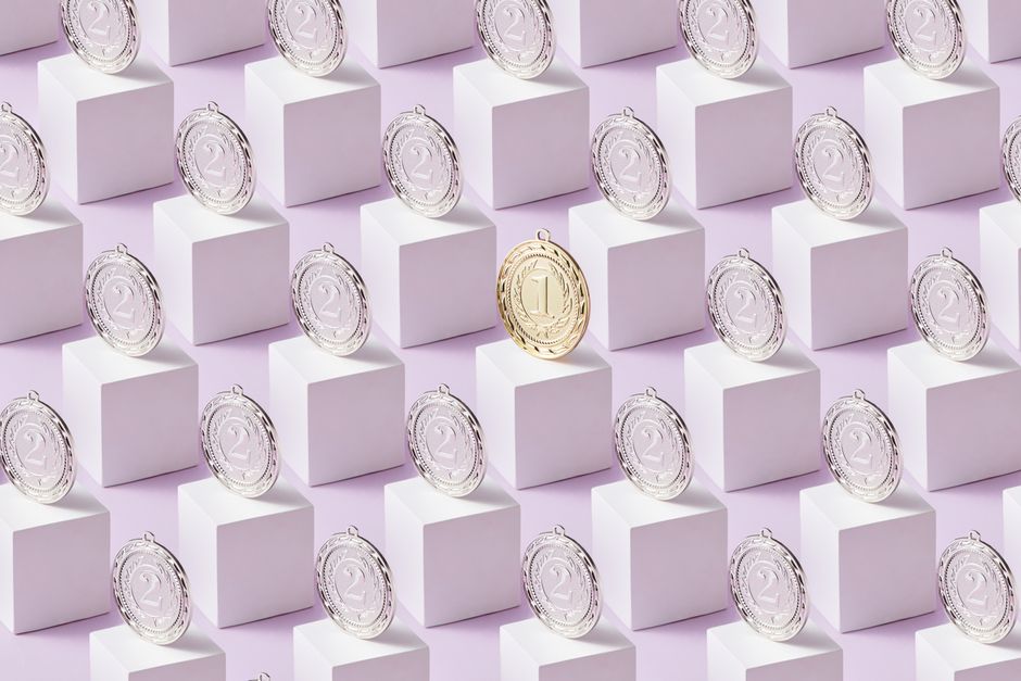 A gold medal stands out among silver medals on white cubes, showcasing uniqueness.