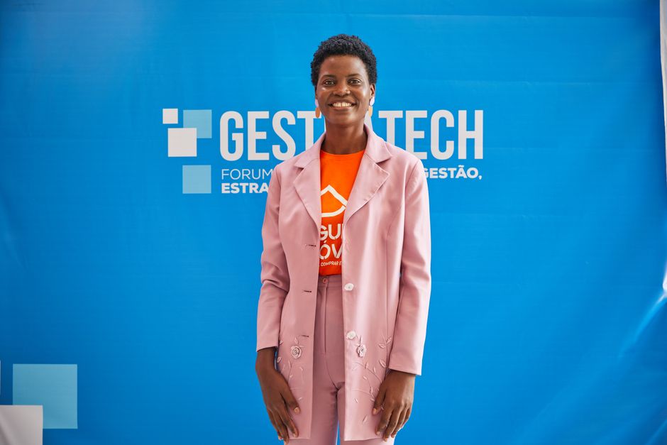 Elegant African woman smiling at a business event. Captured in front of a vibrant blue backdrop.