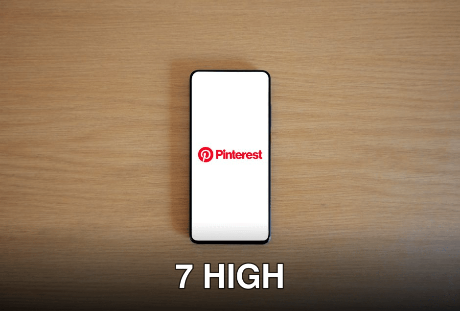 Smartphone with Pinterest logo on screen placed on a wooden surface, minimalistic tech concept.