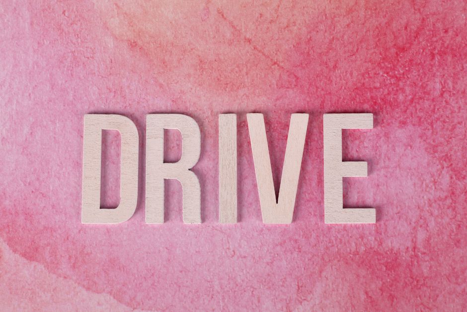 Wooden letters spelling 'Drive' on a textured pink background, inspiring motivation and action.