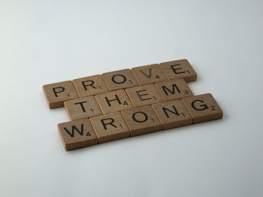Scrabble tiles spelling the motivational phrase 'Prove Them Wrong' on a neutral background.