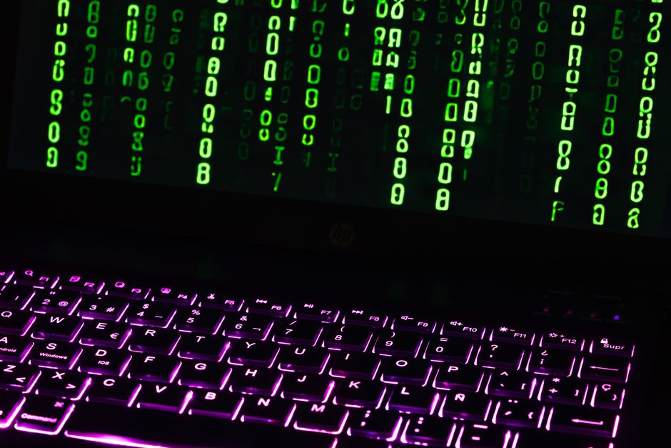 Illuminated laptop keyboard with Matrix-style green code cascading down screen.