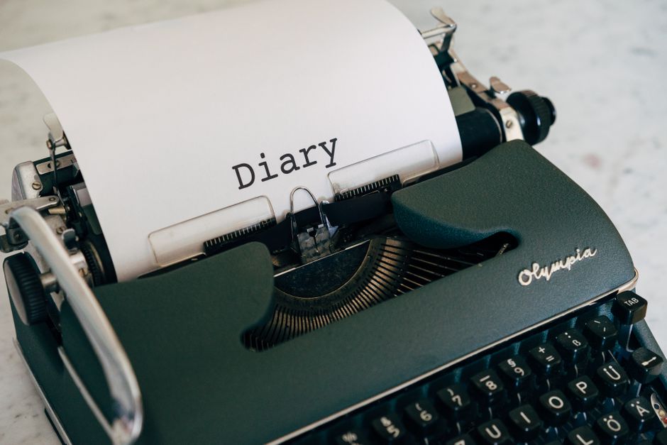 Close-up of a vintage typewriter with a paper titled 'Diary'.