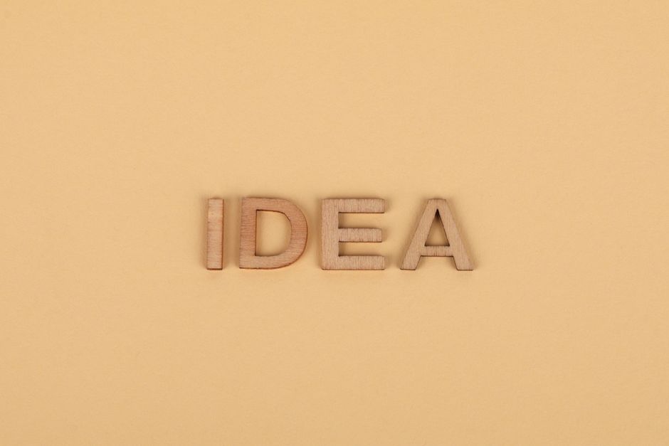 Wooden letters forming 'IDEA' on a plain beige surface, representing creativity.