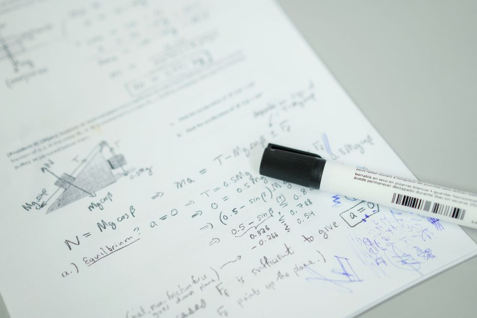 Close-up showing mathematical formulas and a marker on bond paper, ideal for education themes.