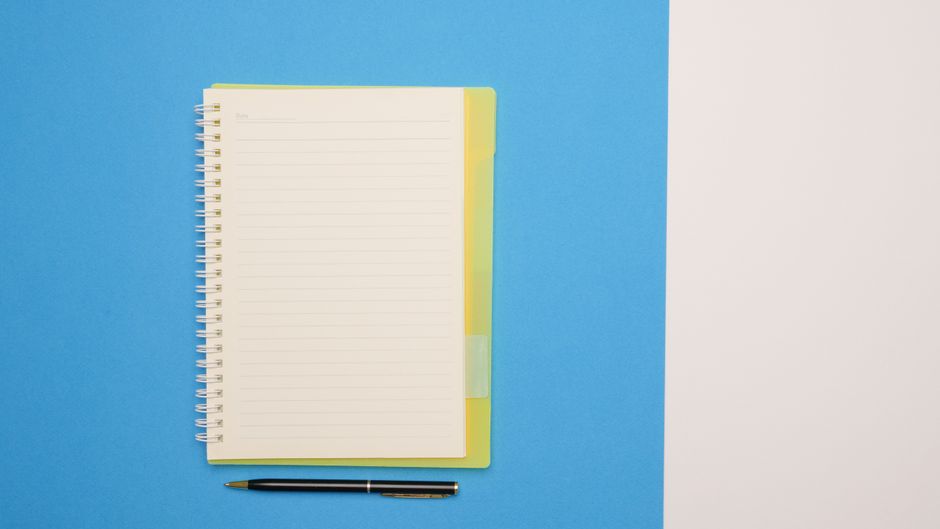 Top view of a spiral notebook and pen on a blue and white surface, ideal for mockups.