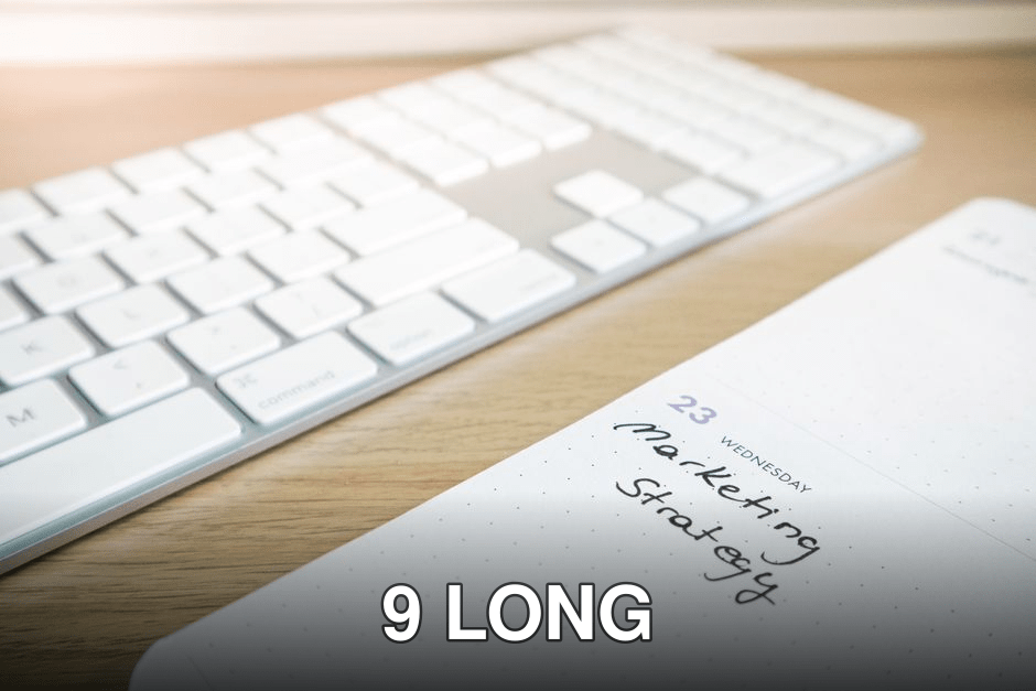 Notebook with marketing strategy note alongside a keyboard on a wooden desk.