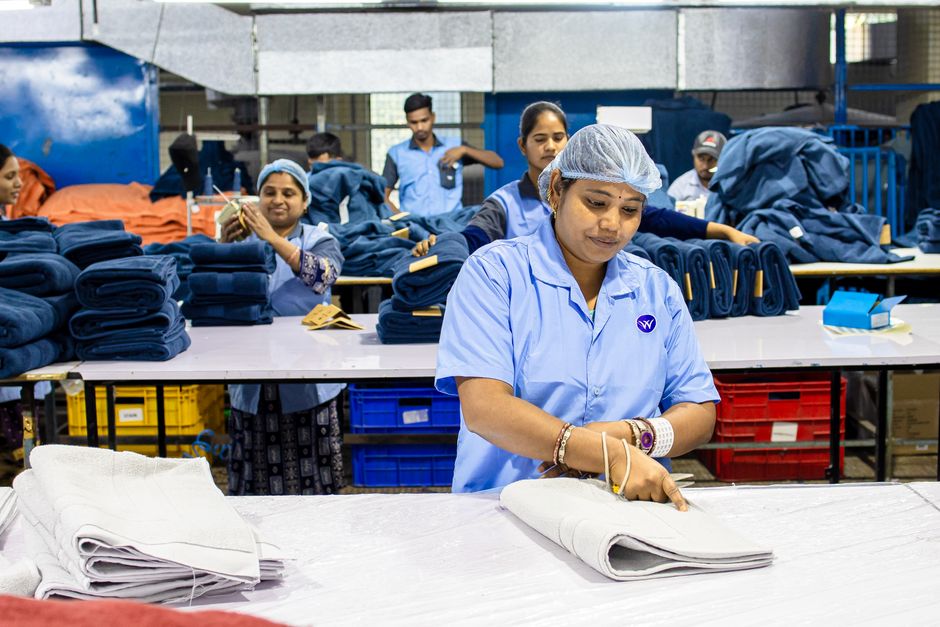 Workers in a textile factory sorting and organizing materials for production. Busy industrial setting.