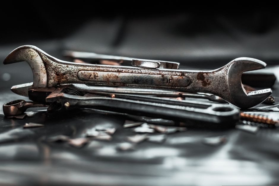 Close-up of rustic tools on a black surface, showcasing a vintage industrial aesthetic.