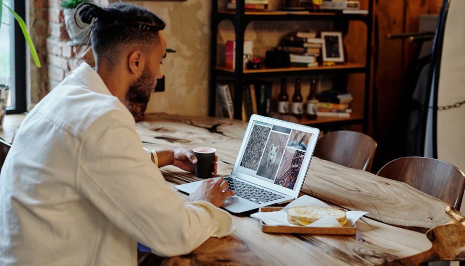 A focused man works on a laptop in a cozy setting, enjoying coffee. Freelance and remote work concept.