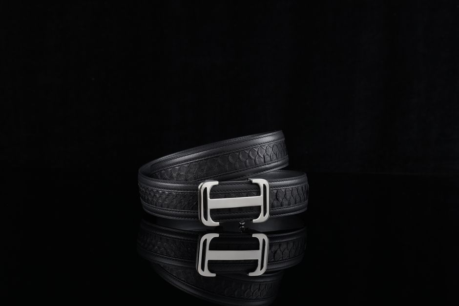 Elegant black leather belt with a silver buckle on a reflective surface, perfect for fashion.