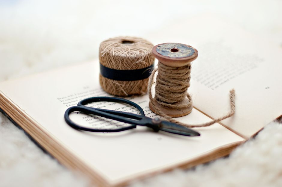 Close-up of scissors and twine on a vintage book, ideal for crafting inspiration.