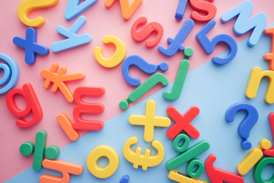 Colorful plastic alphabet magnets scattered on a pastel divided background, ideal for educational graphics.