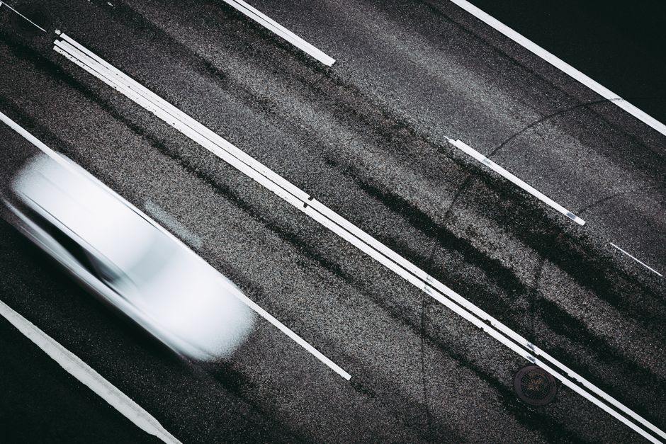 Dynamic overhead view of a highway showcasing motion blur of a passing car.
