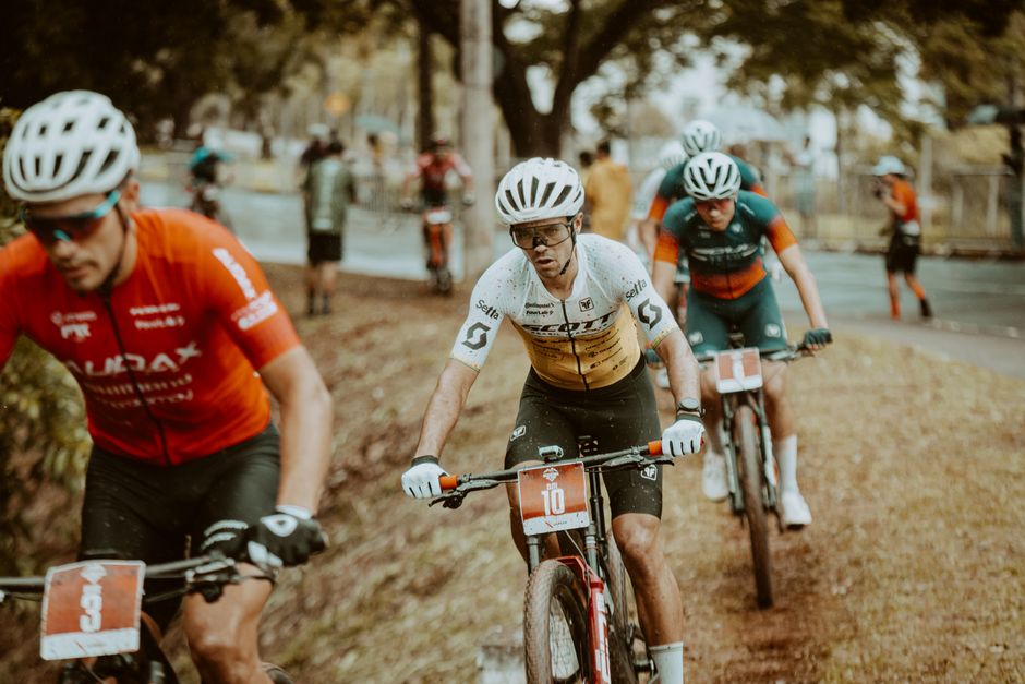 A group of professional cyclists competing in an outdoor race on a rainy day.