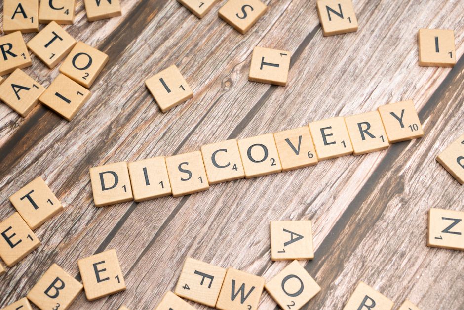 Close-up of wooden letter tiles on a table spelling 'Discovery', representing exploration and creativity.