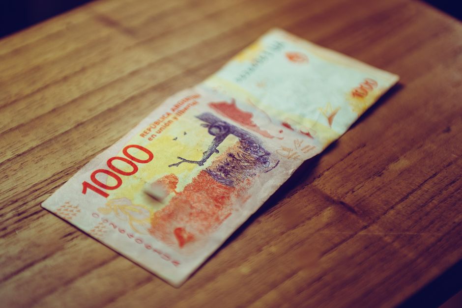 Close-up of 1000 Argentine peso banknote displayed on a wooden table, focusing on currency details.