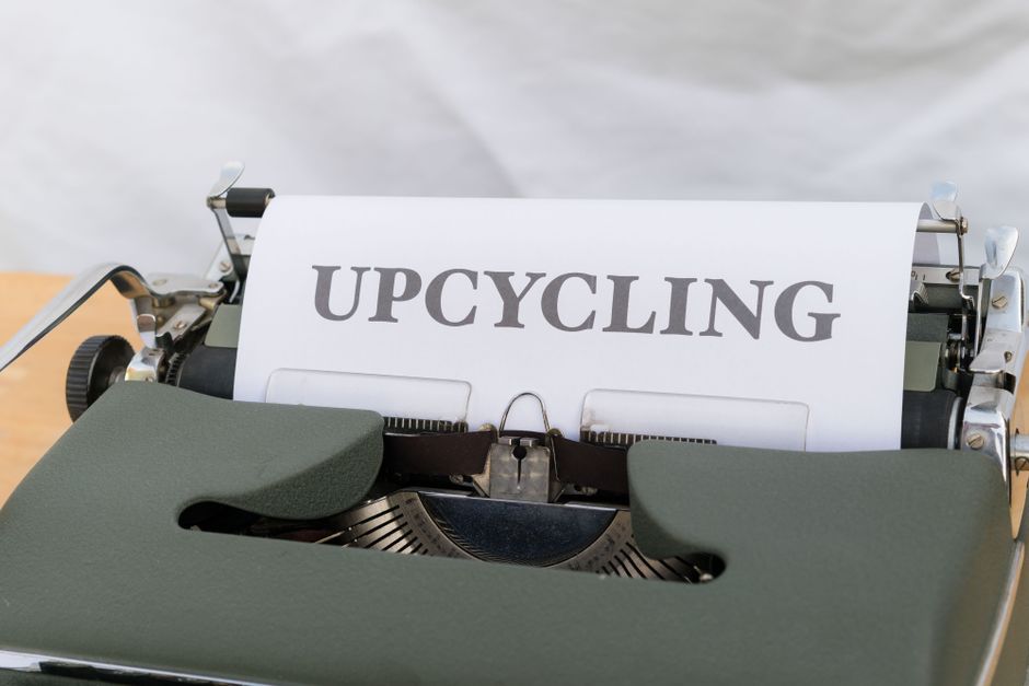 A close-up of a vintage typewriter displaying the word 'UPCYCLING' on its paper.
