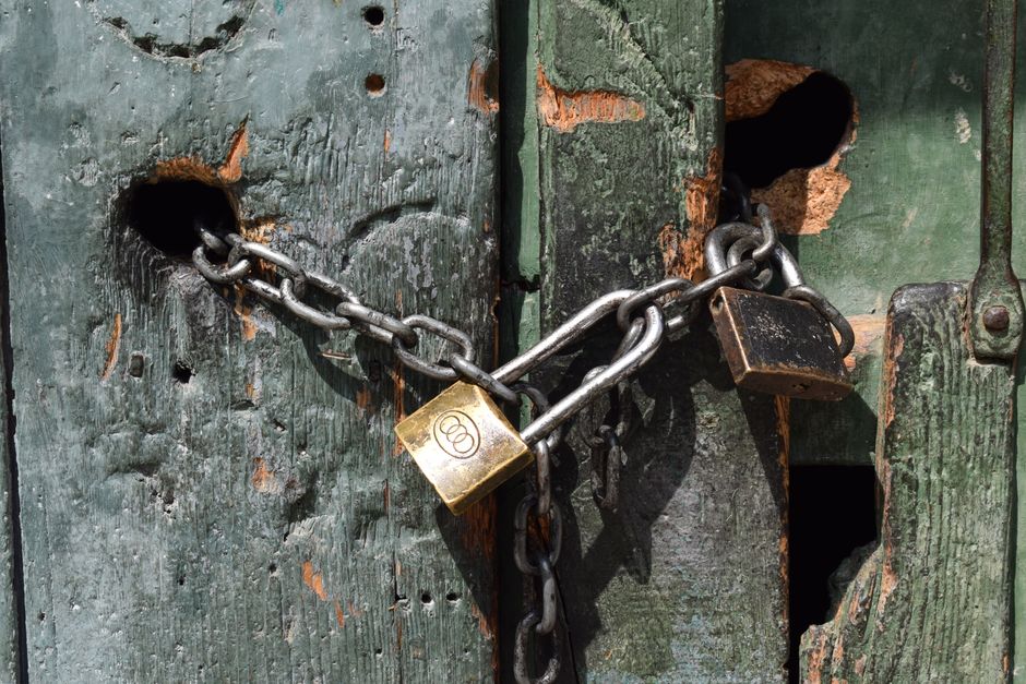 Close-up of a chained and padlocked weathered wooden door.