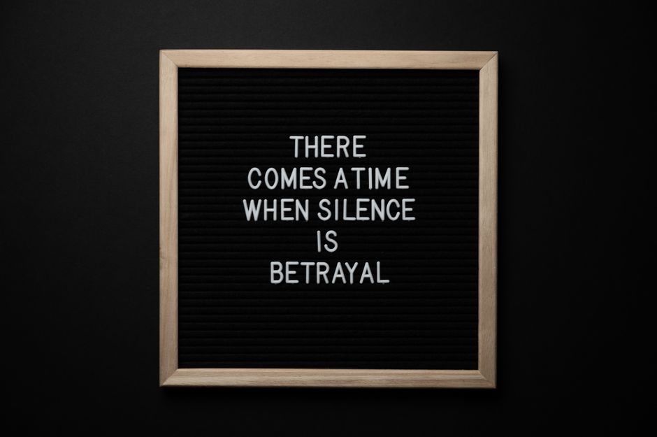 From above chalkboard with THERE COMES A TIME WHEN SILENCE IS BETRAYAL inscription on black background