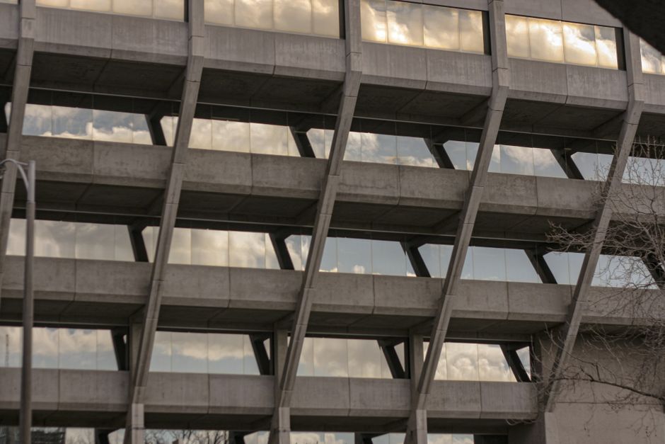 Concrete geometric facade of a Brutalist building in Geelong, reflecting clouds in its windows.