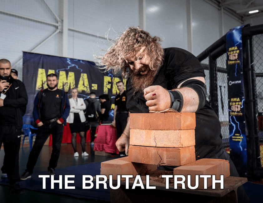 A strongman breaks bricks in an impressive display of power during a competition indoors.