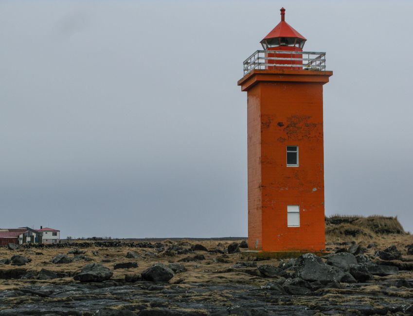 Vibrant orange lighthouse standing against a cloudy sky on a rocky shoreline.