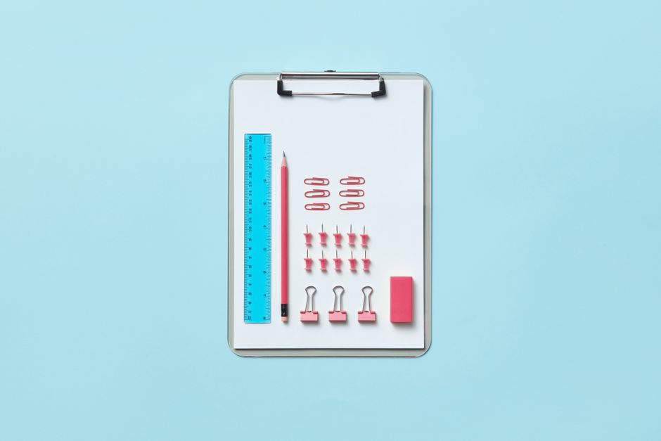 Neatly arranged office supplies on clipboard creating an organized flat lay.