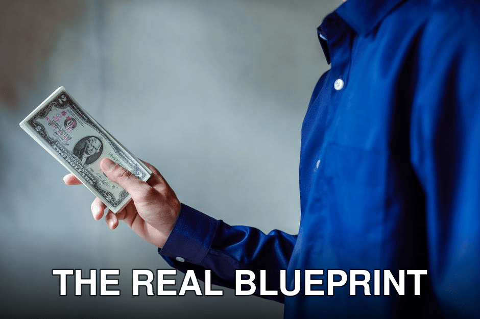 A person in a blue shirt holding a stack of US dollar bills, symbolizing wealth and finance.