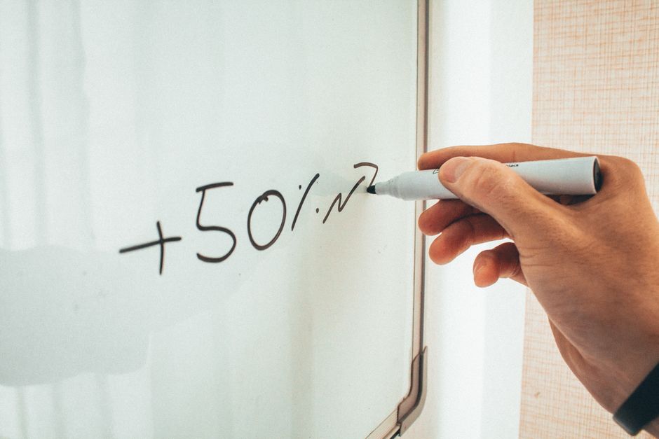 Crop anonymous male teacher writing math formulas on whiteboard during lessons in modern classroom