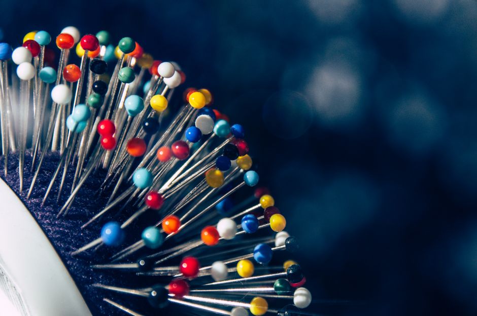 Close-up of assorted colorful push pins arranged artistically on a dark backdrop.